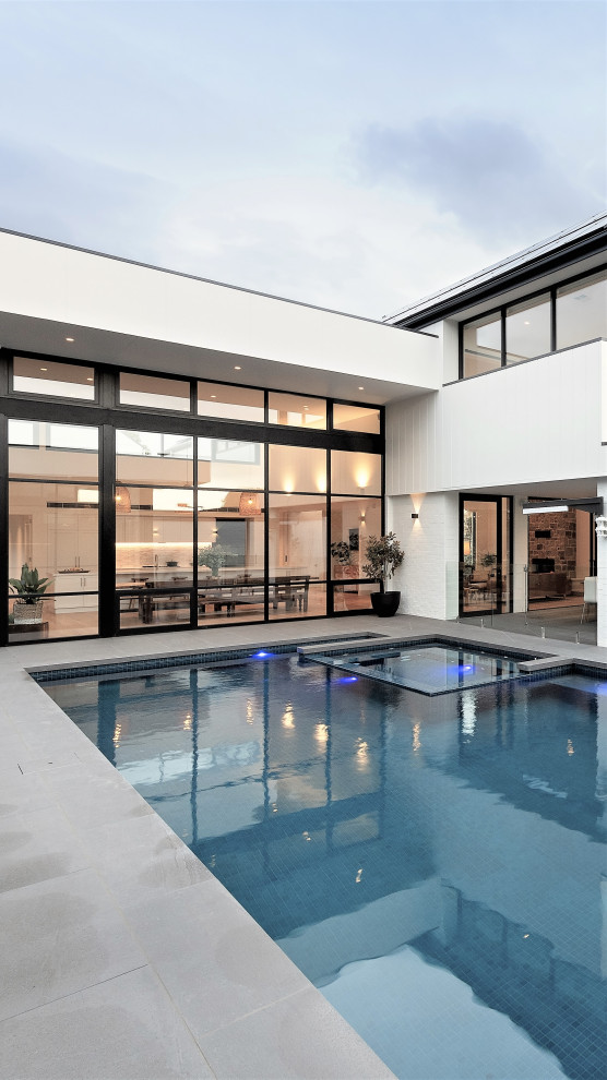 Esempio di una piscina moderna rettangolare di medie dimensioni e dietro casa con una dépendance a bordo piscina e pavimentazioni in cemento