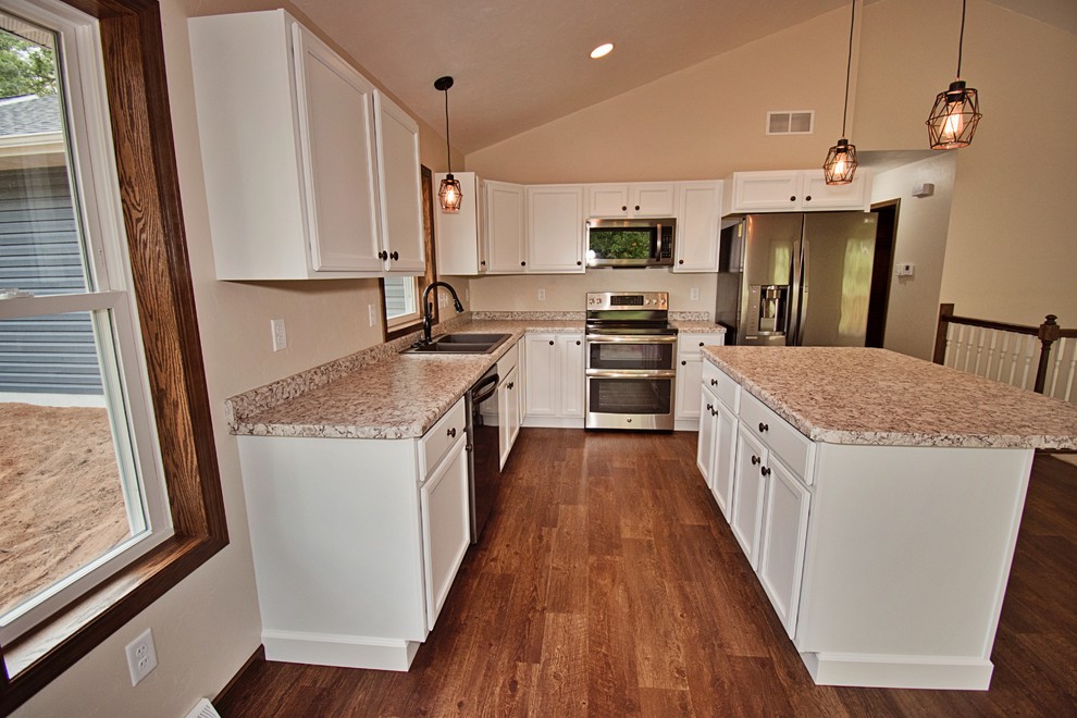 Open concept kitchen - mid-sized transitional l-shaped medium tone wood floor and brown floor open concept kitchen idea with a double-bowl sink, recessed-panel cabinets, white cabinets, laminate countertops, stainless steel appliances, an island and beige countertops