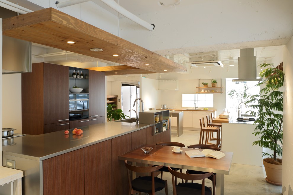 Photo of a contemporary l-shaped kitchen in Tokyo with a single-bowl sink, flat-panel cabinets, medium wood cabinets, stainless steel benchtops, concrete floors, with island and grey floor.