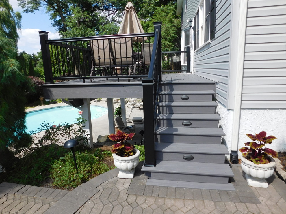 Example of a mid-sized transitional backyard deck design with no cover