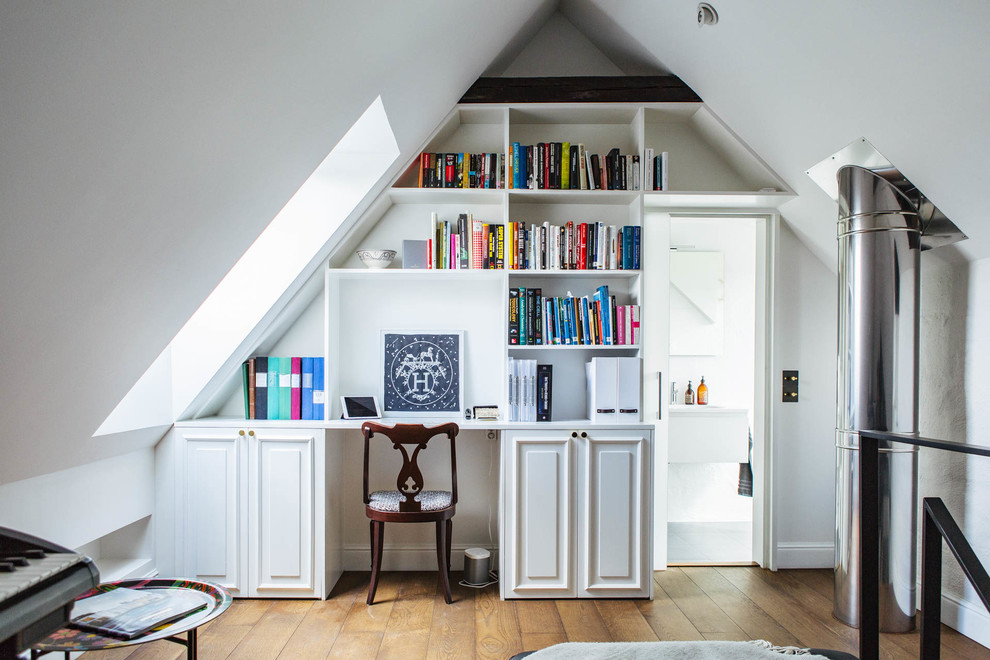 Mid-sized traditional home office in Stockholm with white walls, medium hardwood floors and a built-in desk.