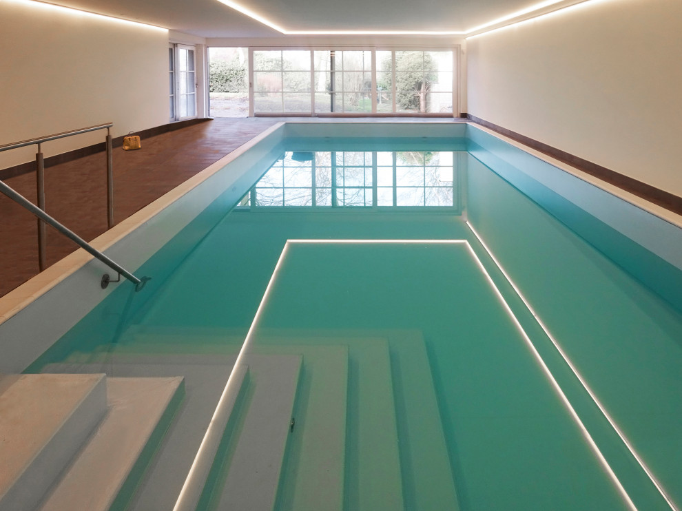 Cette image montre une très grande piscine intérieure rustique rectangle avec du carrelage.