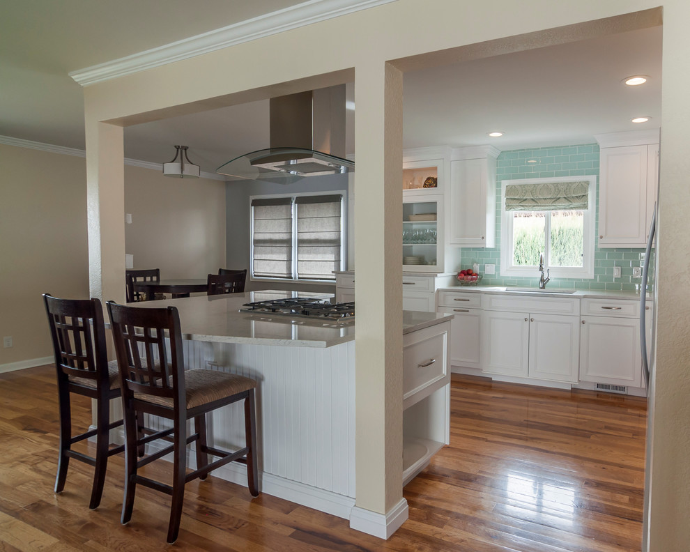 Inspiration for a mid-sized transitional medium tone wood floor eat-in kitchen remodel in Denver with a single-bowl sink, flat-panel cabinets, yellow cabinets, quartz countertops, blue backsplash, glass tile backsplash, white appliances and an island