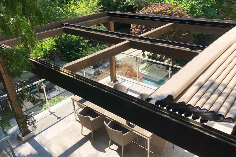 Inspiration för moderna terrasser på baksidan av huset, med en pergola och räcke i glas