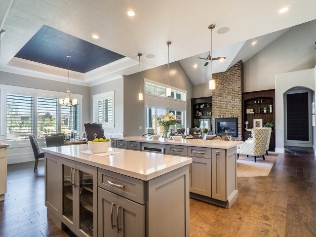 Design ideas for a mid-sized transitional l-shaped open plan kitchen in Salt Lake City with shaker cabinets, grey cabinets, quartzite benchtops, multiple islands, black splashback, glass tile splashback, stainless steel appliances, an undermount sink and medium hardwood floors.