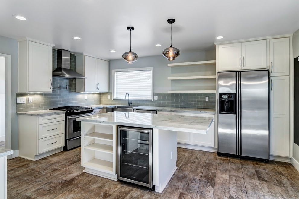 Design ideas for a mid-sized modern l-shaped eat-in kitchen in San Diego with a farmhouse sink, recessed-panel cabinets, white cabinets, marble benchtops, grey splashback, ceramic splashback, stainless steel appliances, porcelain floors and with island.