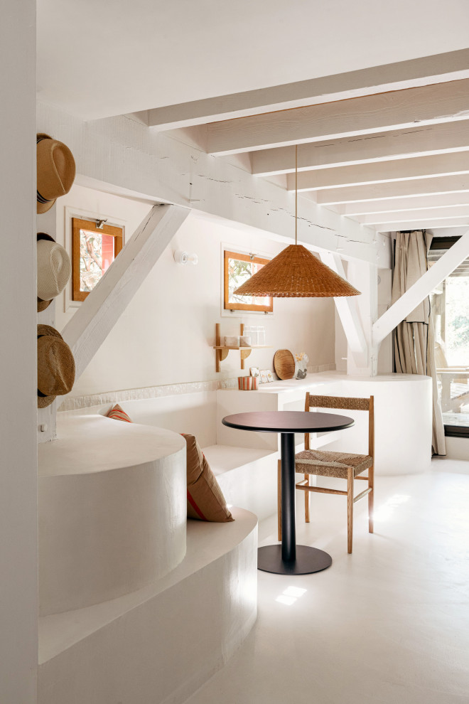 Réalisation d'une salle à manger méditerranéenne avec sol en béton ciré, un sol blanc, un plafond en bois et un mur en parement de brique.