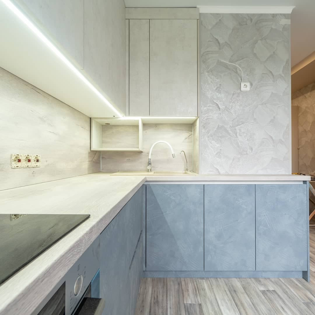 Большая угловая кухня в синем и белом цвете с фасадами под камень