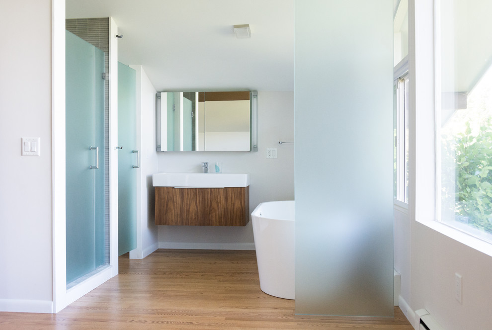This is an example of a large midcentury master bathroom in Boston with flat-panel cabinets, dark wood cabinets, a freestanding tub, white walls, light hardwood floors, an integrated sink and an alcove shower.