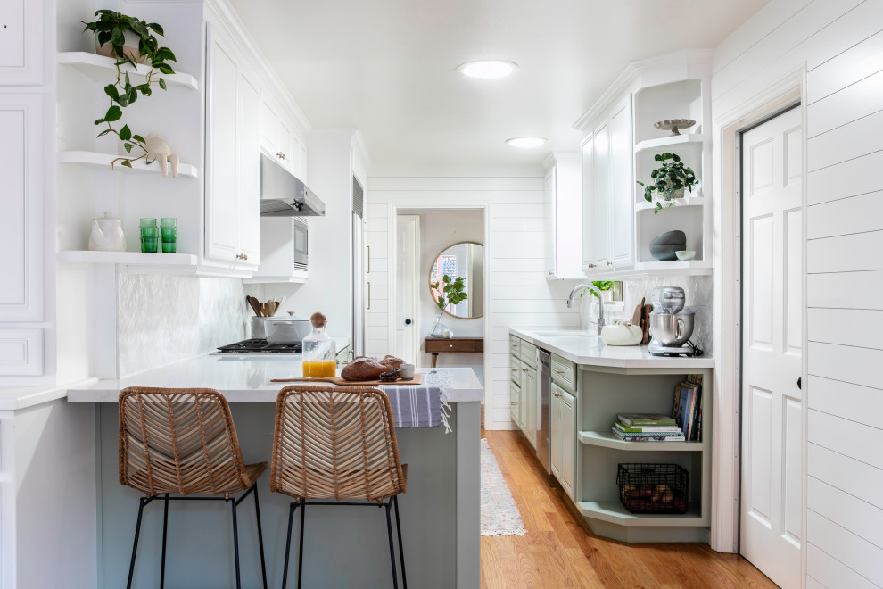 Design ideas for a small country galley separate kitchen in San Francisco with a drop-in sink, raised-panel cabinets, green cabinets, quartz benchtops, white splashback, cement tile splashback, stainless steel appliances, light hardwood floors, a peninsula and white benchtop.