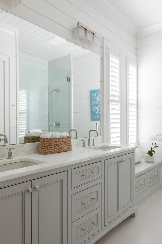 Exempel på ett stort maritimt vit vitt en-suite badrum, med luckor med infälld panel, grå skåp, våtrum, grå kakel, keramikplattor, vita väggar, ett integrerad handfat, marmorbänkskiva, beiget golv och dusch med gångjärnsdörr