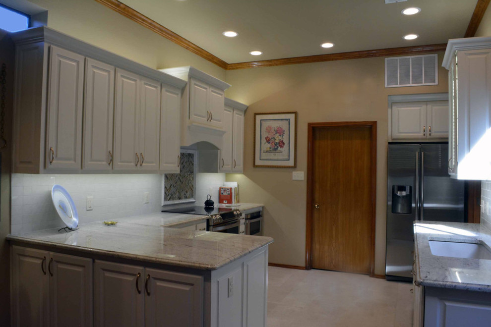 Example of a mid-sized minimalist l-shaped ceramic tile eat-in kitchen design in Dallas with a single-bowl sink, raised-panel cabinets, white cabinets, granite countertops, white backsplash, subway tile backsplash, stainless steel appliances and a peninsula