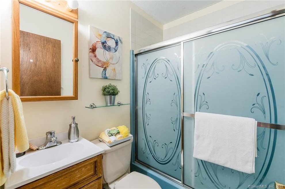 Photo of a small transitional kids bathroom in Bridgeport with furniture-like cabinets, a drop-in tub, a shower/bathtub combo, a one-piece toilet, white tile, porcelain tile, beige walls, ceramic floors, a console sink, solid surface benchtops, blue floor, a sliding shower screen and white benchtops.