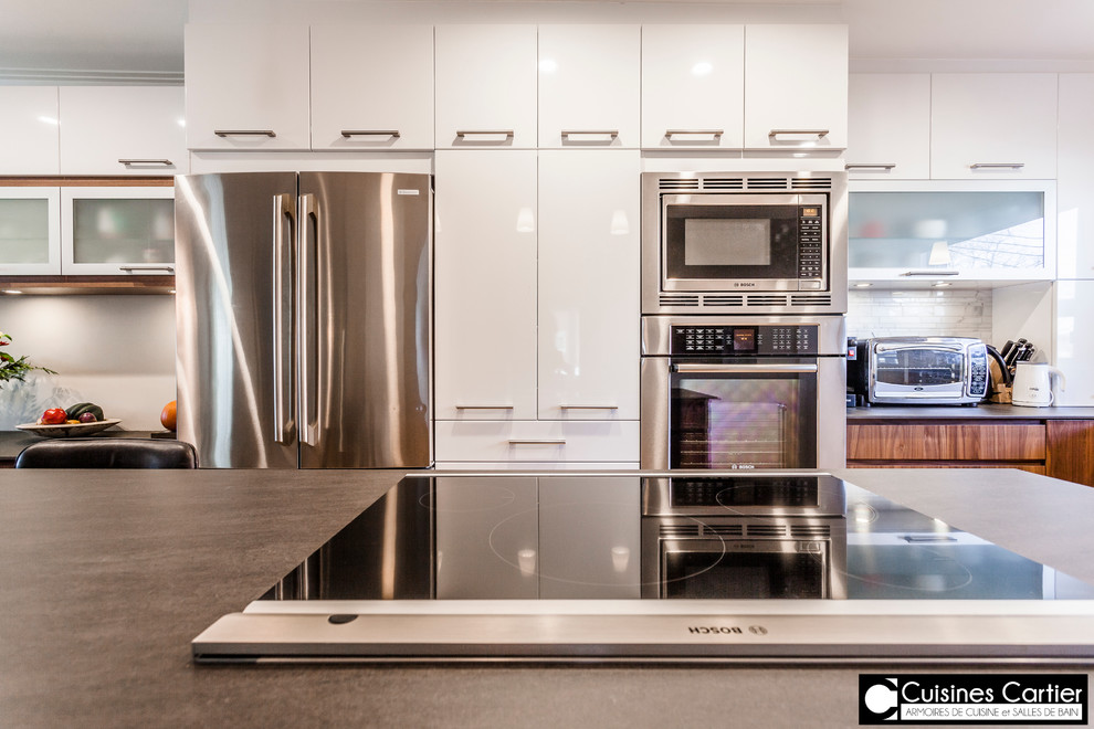 Large transitional galley medium tone wood floor eat-in kitchen photo in Montreal with an undermount sink, flat-panel cabinets, dark wood cabinets, quartzite countertops, white backsplash, mosaic tile backsplash, stainless steel appliances and an island