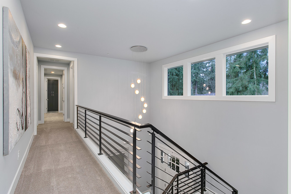 Large transitional hallway in Seattle with grey walls and carpet.