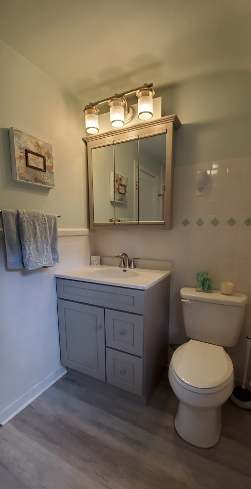 Mid-sized transitional bathroom in New York with shaker cabinets, grey cabinets, white tile, ceramic tile, green walls, vinyl floors, solid surface benchtops, grey floor, white benchtops, a single vanity and a freestanding vanity.