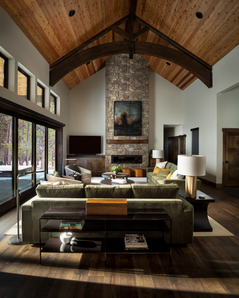 Exemple d'un grand salon chic avec un sol en bois brun, une cheminée standard, un manteau de cheminée en pierre de parement et un plafond en bois.