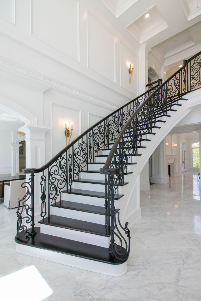 Staircase - huge transitional wooden curved mixed material railing and wainscoting staircase idea in DC Metro with wooden risers