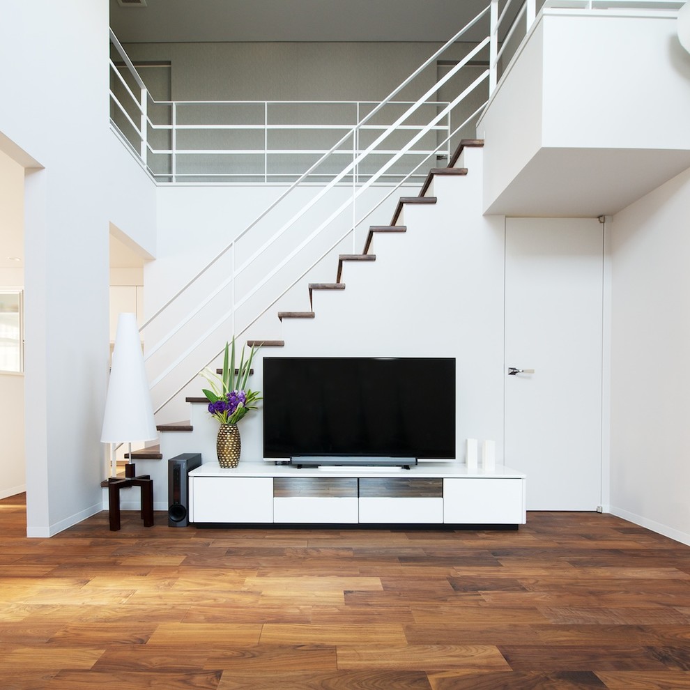 This is an example of a modern living room in Other with a freestanding tv, grey walls, dark hardwood floors and brown floor.