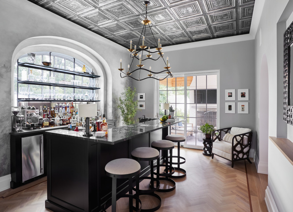 Inspiration for a transitional u-shaped seated home bar in New York with recessed-panel cabinets, black cabinets, marble benchtops, medium hardwood floors, brown floor and multi-coloured benchtop.