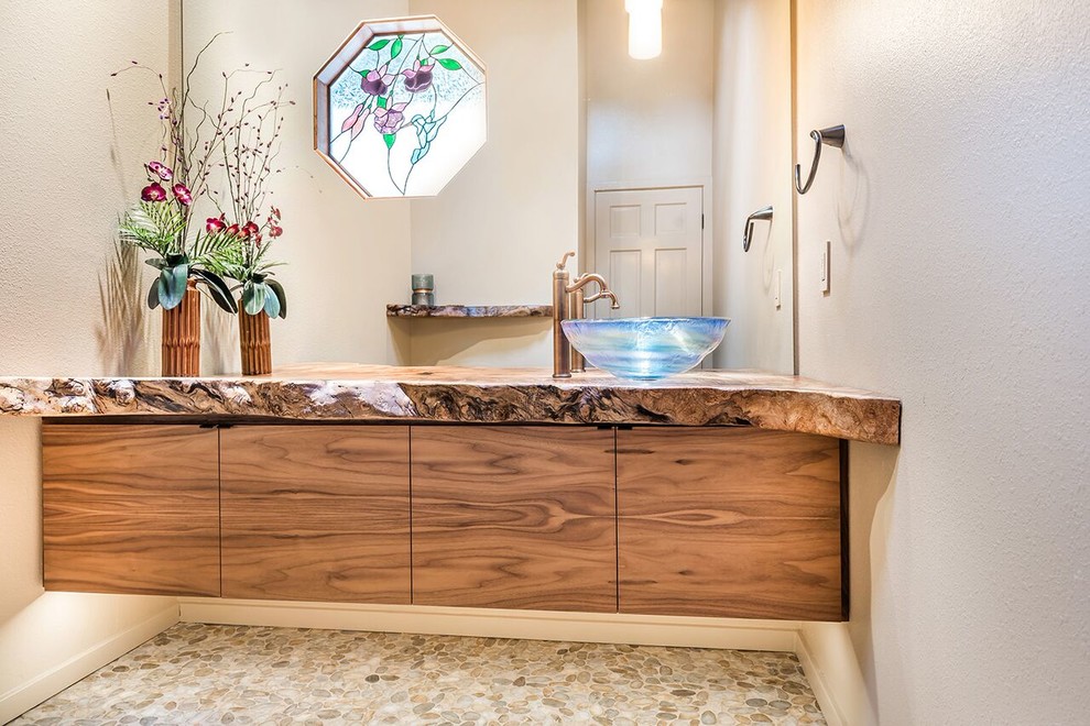 Photo of a mid-sized country 3/4 bathroom in San Francisco with flat-panel cabinets, medium wood cabinets, a two-piece toilet, beige walls, pebble tile floors, a vessel sink and wood benchtops.