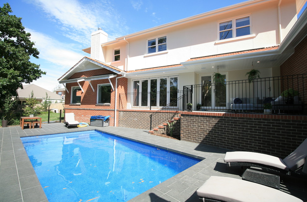 Photo of a mid-sized arts and crafts side yard rectangular pool in Melbourne with natural stone pavers.