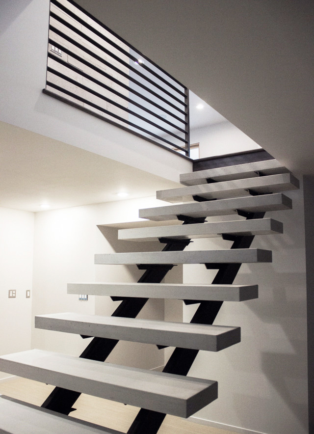 This is an example of a large modern concrete floating staircase in Salt Lake City with open risers and metal railing.