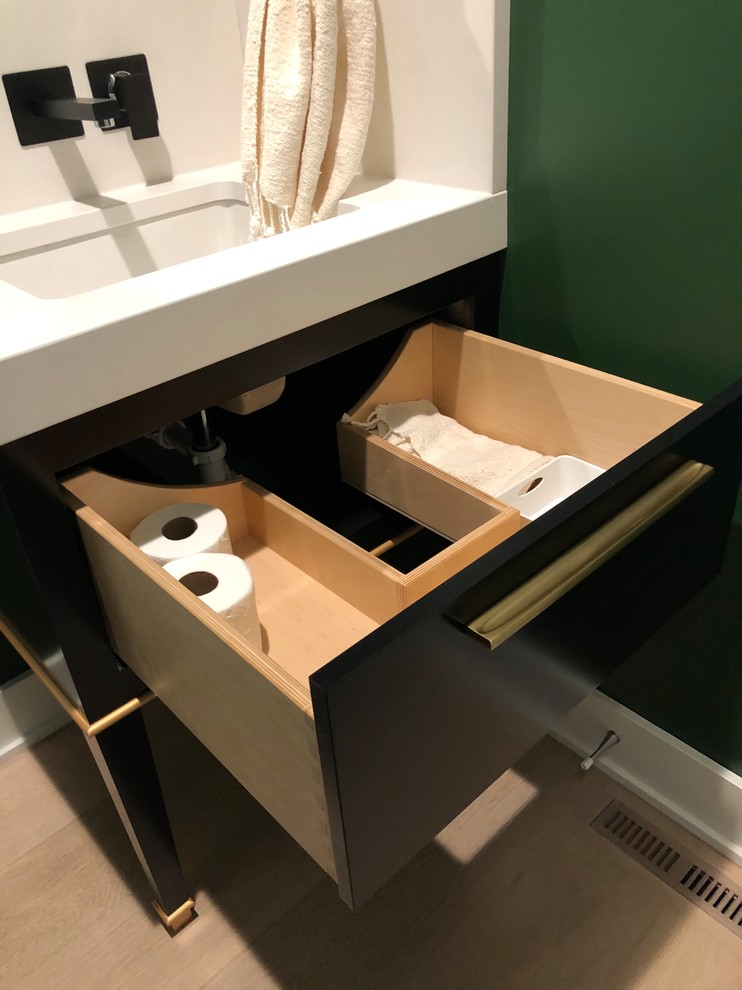Inspiration for a small modern powder room in Omaha with furniture-like cabinets, black cabinets, a one-piece toilet, yellow tile, stone slab, green walls, light hardwood floors, an undermount sink, engineered quartz benchtops, brown floor and white benchtops.