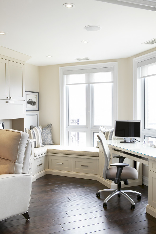 Traditional home office in Toronto with beige walls, dark hardwood floors and a built-in desk.