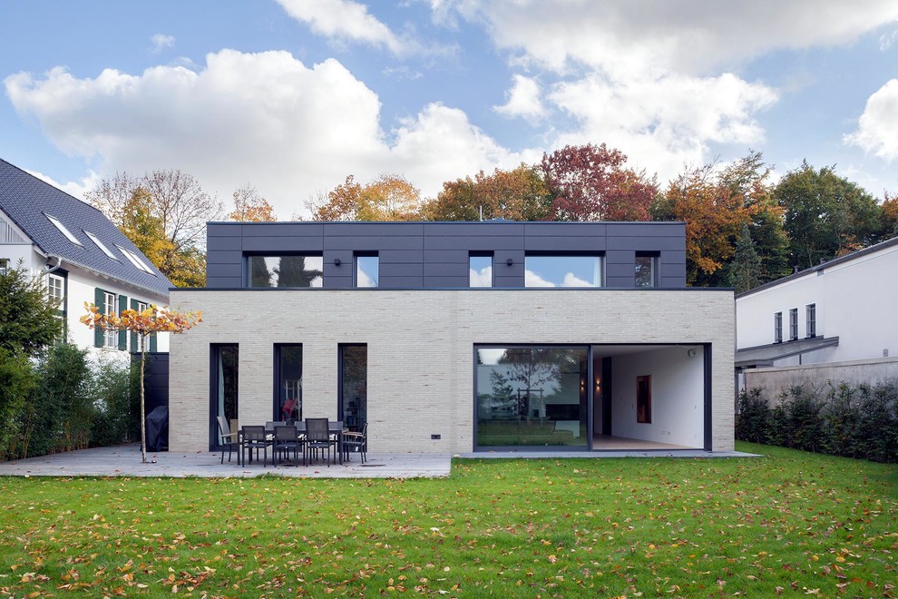 Design ideas for a mid-sized contemporary two-storey grey exterior in Cologne with stone veneer and a flat roof.