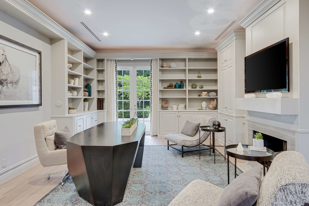 Photo of a mid-sized transitional study room in Miami with a standard fireplace, a freestanding desk, beige floor, beige walls, light hardwood floors and a tile fireplace surround.