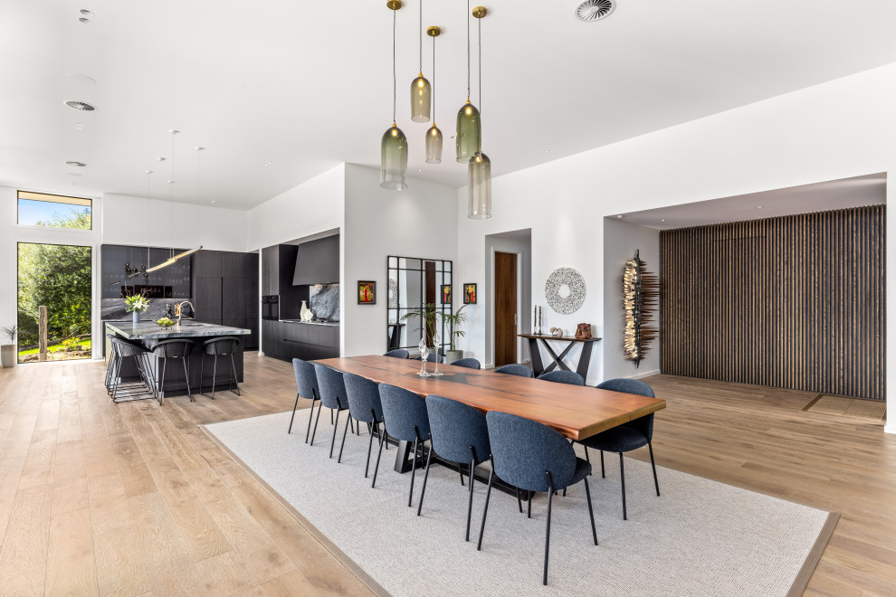 Photo of an expansive midcentury open plan dining in Other with white walls, light hardwood floors and white floor.