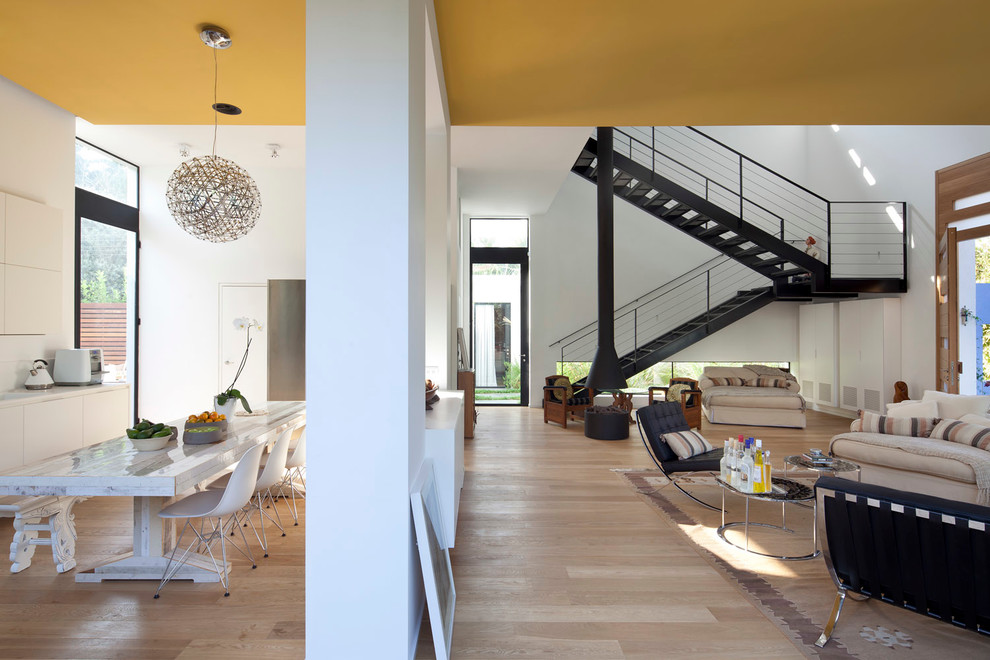 Inspiration for a contemporary open concept living room in Tel Aviv with white walls and light hardwood floors.