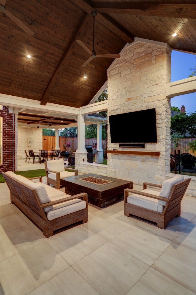 Photo of a large transitional backyard patio in Houston with a fire feature, tile and a roof extension.