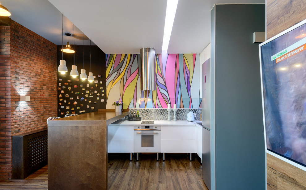 Contemporary l-shaped eat-in kitchen in Moscow with multi-coloured splashback, laminate floors, brown floor, white benchtop, flat-panel cabinets, white cabinets, mosaic tile splashback, stainless steel appliances and a peninsula.
