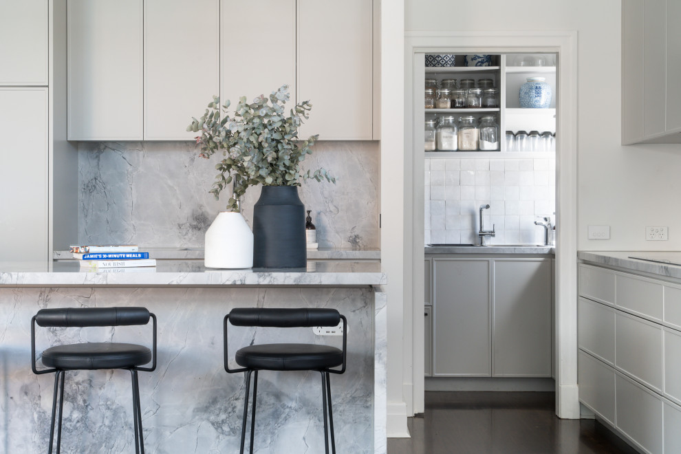 Große Moderne Wohnküche mit Unterbauwaschbecken, Schrankfronten im Shaker-Stil, grauen Schränken, Granit-Arbeitsplatte, Küchenrückwand in Grau, Rückwand aus Granit, schwarzen Elektrogeräten, dunklem Holzboden, Kücheninsel, braunem Boden und grauer Arbeitsplatte in Melbourne