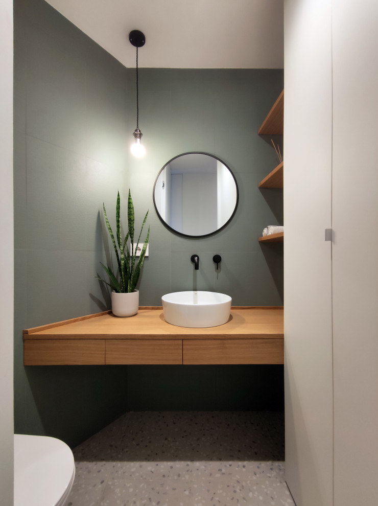 This is an example of a small contemporary utility room in Milan with light wood cabinets, wood benchtops, green splashback, porcelain splashback, green walls, porcelain floors, a concealed washer and dryer, multi-coloured floor and recessed.