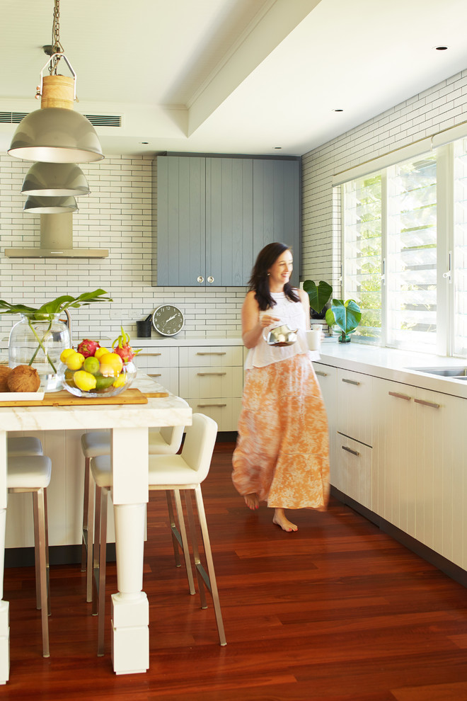 Design ideas for a large beach style u-shaped eat-in kitchen in Perth with an undermount sink, flat-panel cabinets, marble benchtops, white splashback, subway tile splashback, medium hardwood floors and with island.