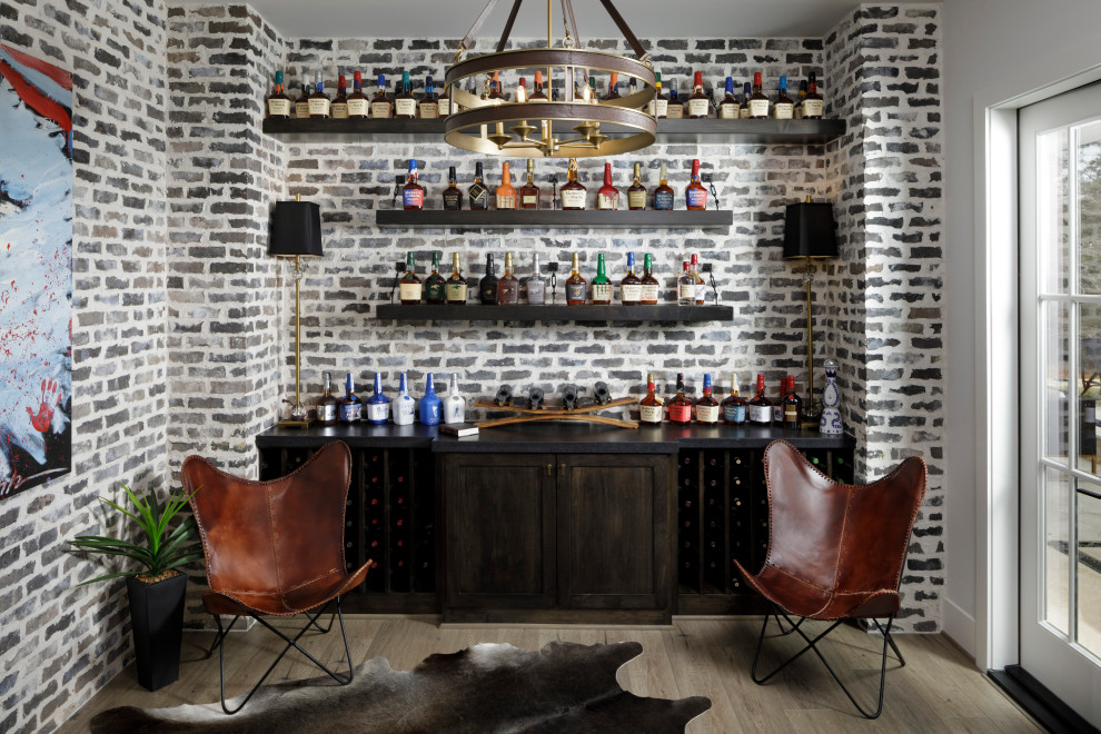 Inspiration for a mid-sized transitional single-wall home bar in Houston with dark wood cabinets, grey splashback, brick splashback, laminate floors, brown floor and black benchtop.