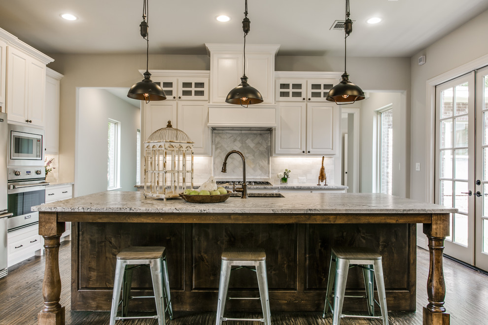 Design ideas for a mid-sized traditional l-shaped kitchen in Dallas with a double-bowl sink, raised-panel cabinets, white cabinets, granite benchtops, grey splashback, dark hardwood floors, with island and stainless steel appliances.