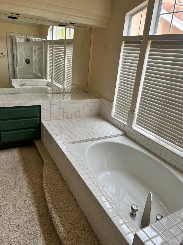 Foto på ett stort vit en-suite badrum, med gröna skåp, ett platsbyggt badkar, en hörndusch, vit kakel, kaklad bänkskiva, dusch med gångjärnsdörr, gula väggar och beiget golv
