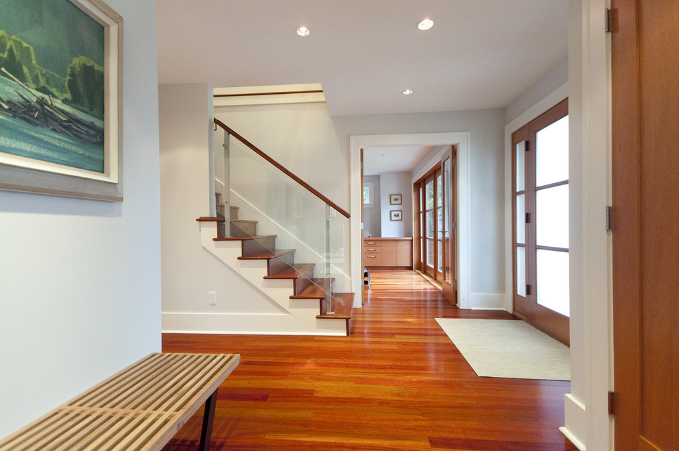 This is an example of a contemporary foyer in Vancouver with medium hardwood floors, a single front door, a glass front door and orange floor.