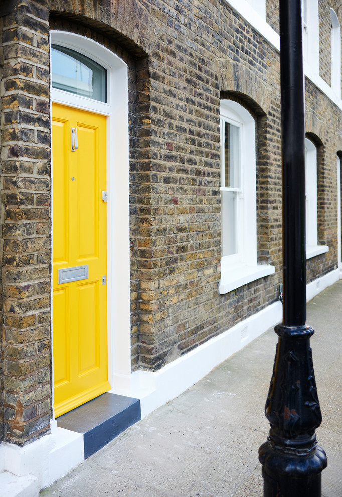 Inspiration for a mid-sized scandinavian front door in London with multi-coloured walls, concrete floors, a single front door, a yellow front door and grey floor.