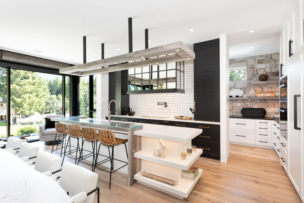 Inspiration for a transitional medium tone wood floor and brown floor open concept kitchen remodel in Vancouver with an undermount sink, shaker cabinets, white backsplash, subway tile backsplash, paneled appliances, an island and white countertops