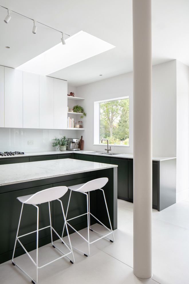 This is an example of a mid-sized modern l-shaped open plan kitchen in London with a double-bowl sink, flat-panel cabinets, green cabinets, quartz benchtops, ceramic floors, with island, white floor and white benchtop.