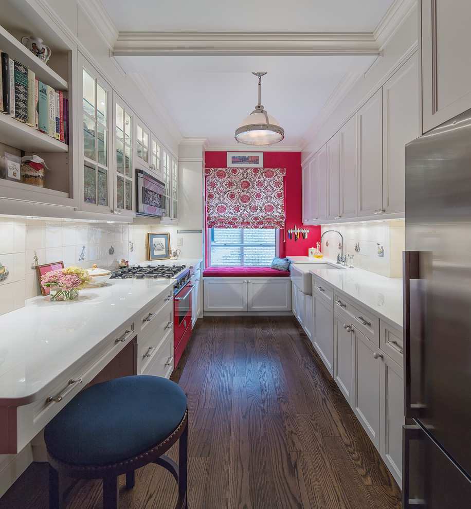 Design ideas for a mid-sized traditional galley kitchen in New York with white splashback, dark hardwood floors, a farmhouse sink, recessed-panel cabinets, white cabinets, coloured appliances and no island.