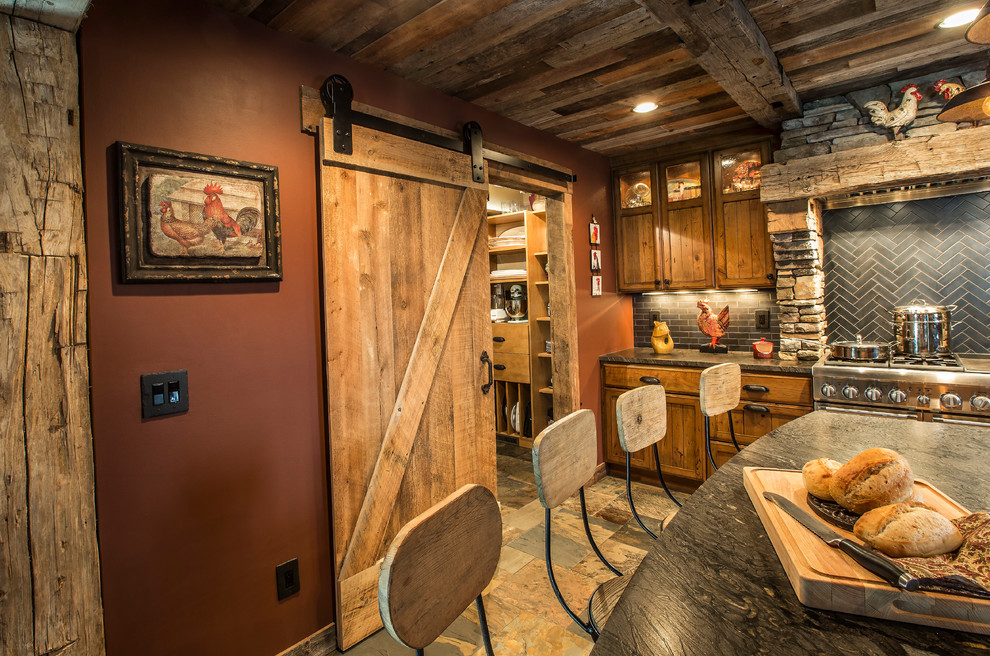 Mountain style slate floor kitchen photo in Minneapolis with a farmhouse sink, flat-panel cabinets, distressed cabinets, granite countertops, black backsplash, porcelain backsplash and stainless steel appliances