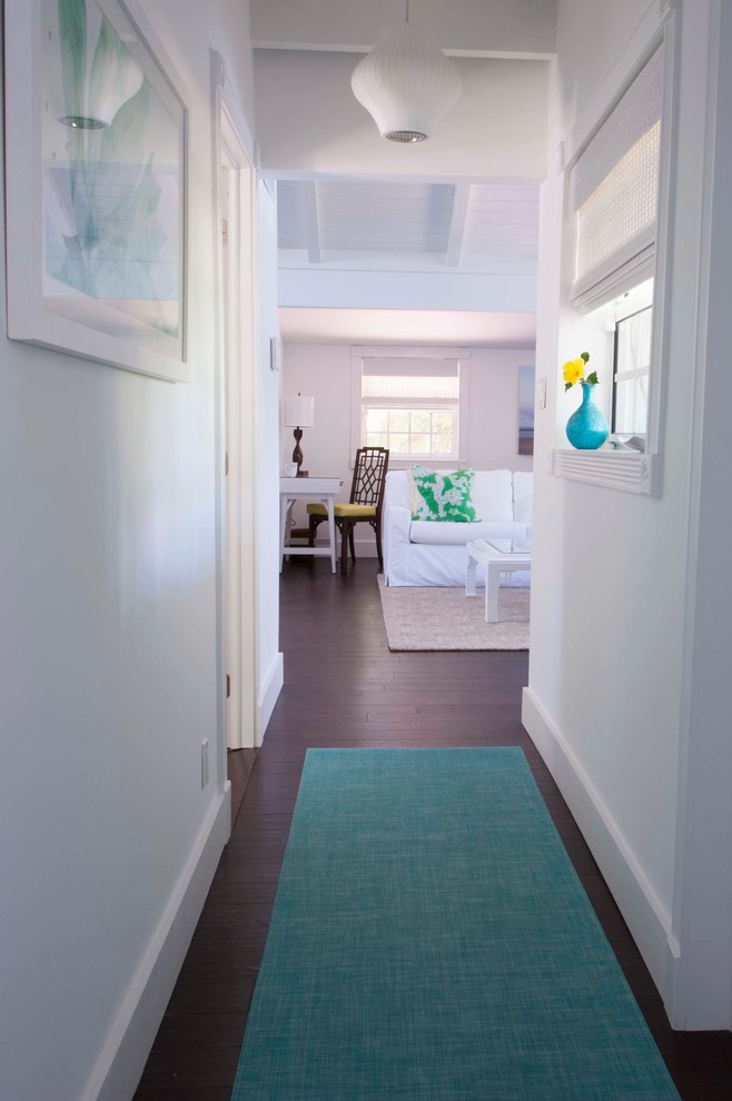 Example of a small beach style dark wood floor hallway design in Other with white walls