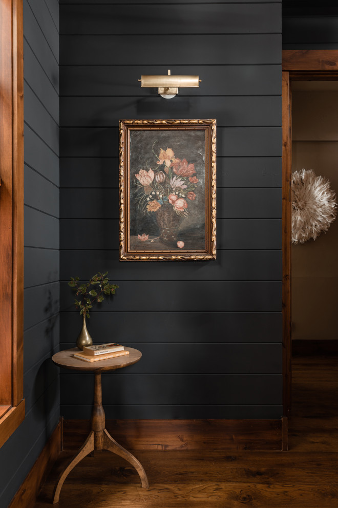 Foto di un piccolo corridoio boho chic con pareti nere, pavimento in legno massello medio, pavimento marrone e pareti in perlinato