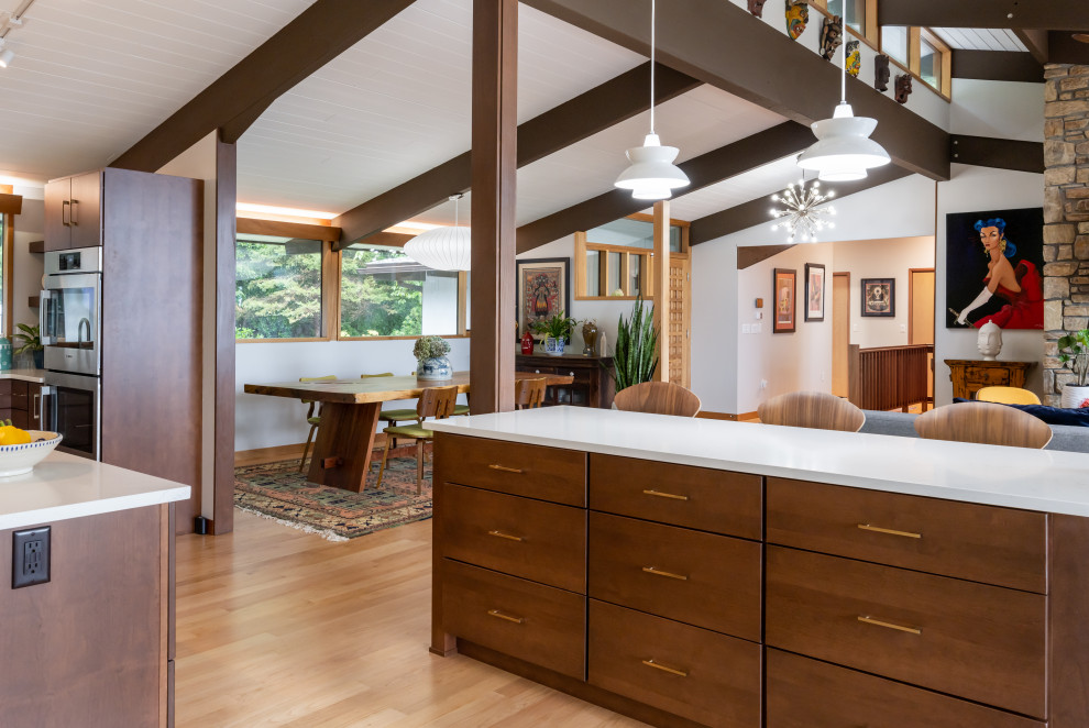 This is an example of a mid-sized midcentury u-shaped kitchen in Other with a single-bowl sink, flat-panel cabinets, medium wood cabinets, quartzite benchtops, green splashback, porcelain splashback, stainless steel appliances, light hardwood floors, with island, beige floor, white benchtop and exposed beam.